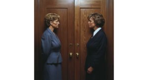 two women facing eachother in front of a closed door