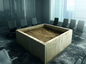 a grave which is a box with dirt in the middle of a boardroom