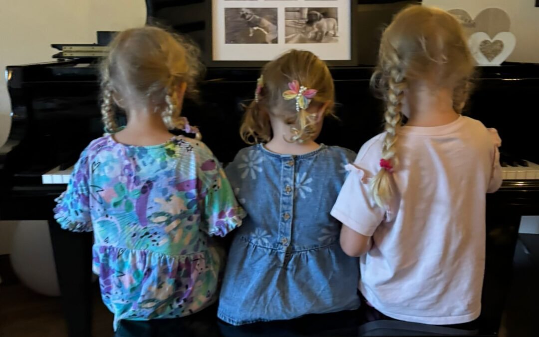 view from the back of 3 girls playing the piano