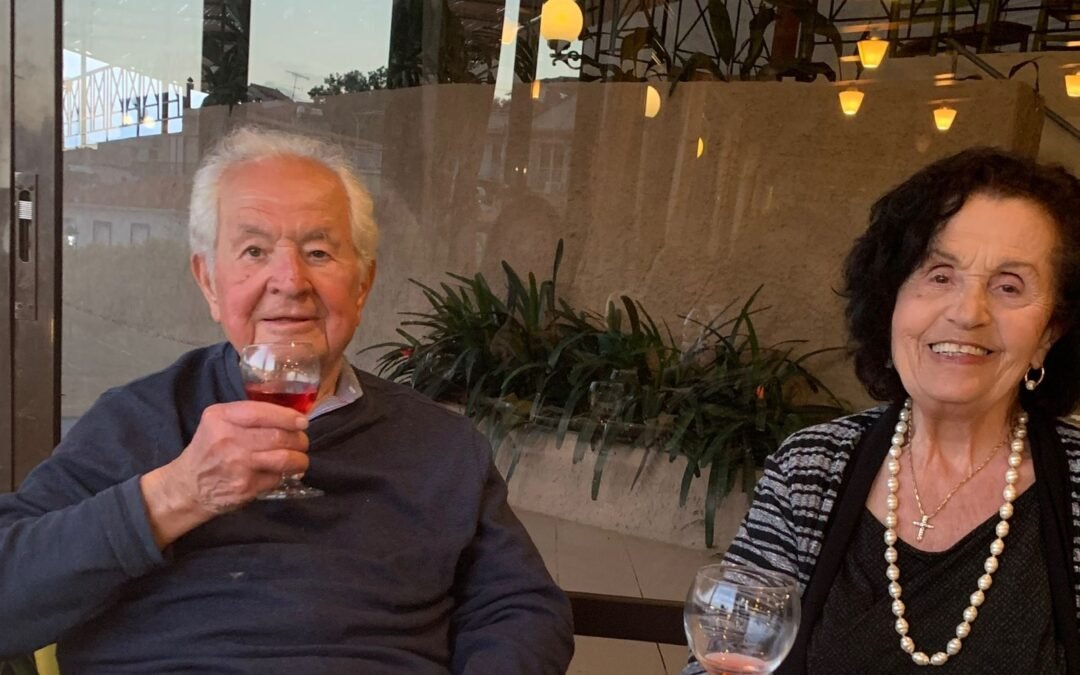 Older Gentleman drinking a small glass of village wine next to his wife.