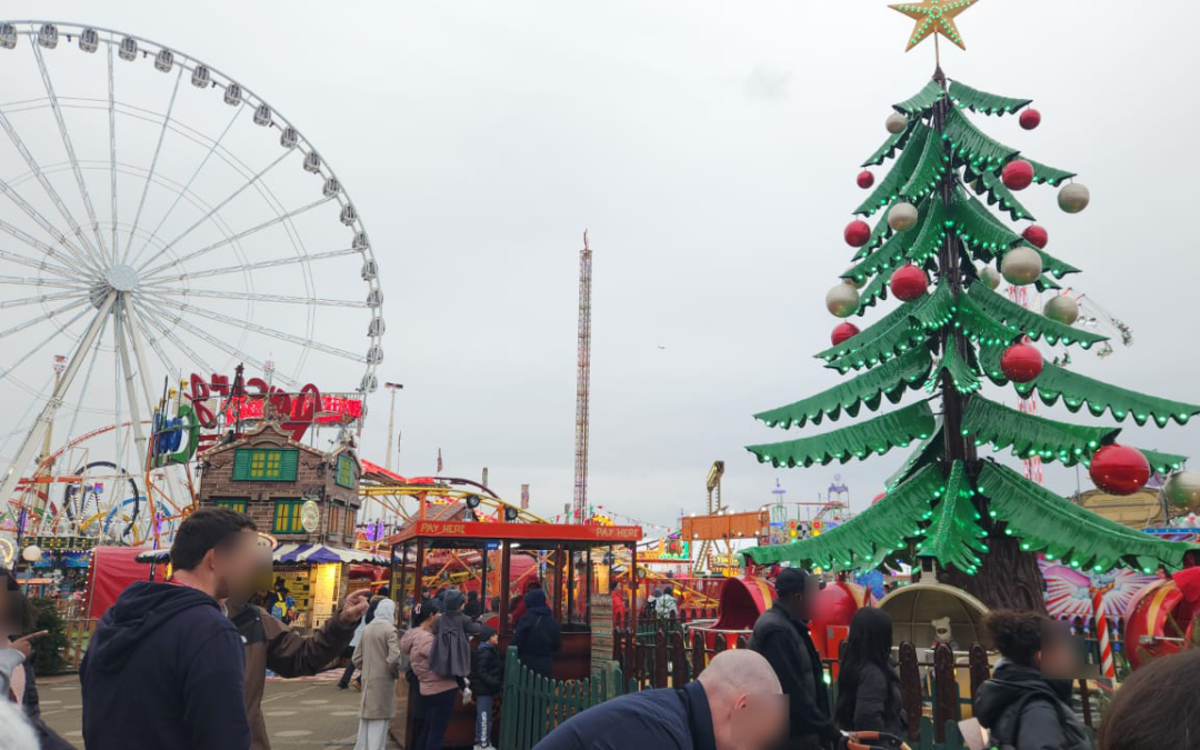 Live shot of Winterwonderland in Hyde park London. you see people, the ferris wheel and the big green tree.