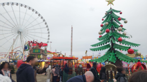 Live shot of Winterwonderland in Hyde park London. you see people, the ferris wheel and the big green tree.