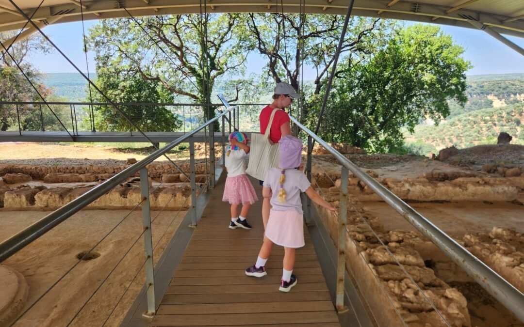 woman and 2 children on a wooden bridge looking below as the ruins of Nestor Palace in Pylos Greece