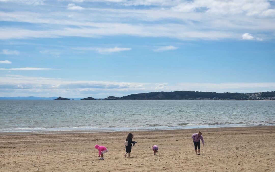 family picking sea shells overlooking Swansea Bay