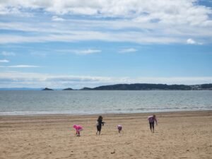 family picking sea shells overlooking Swansea Bay